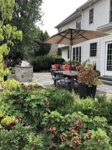 A patio with an umbrella and chairs in the back yard.