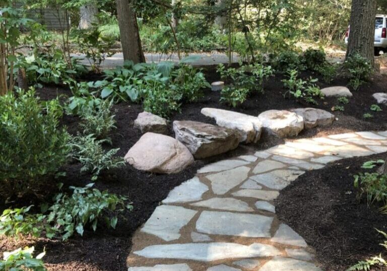 A stone path in the middle of a garden. Home landscape design, landscape design, garden path, landscape maintenance