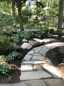 A stone path in the middle of a garden. Home landscape design, landscape design, garden path, landscape maintenance