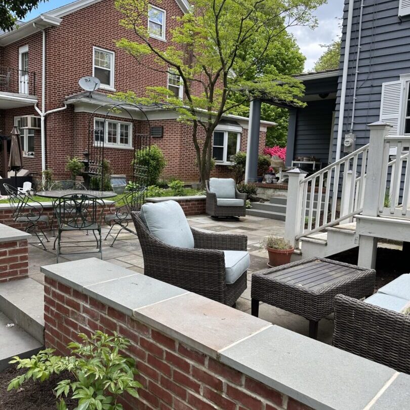 A patio with furniture and plants in the yard.